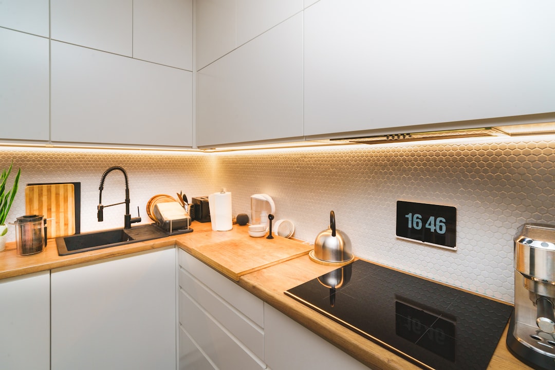 A bright and spacious luxury kitchen featuring minimalist white cabinets, a marble island, and high-end appliances.