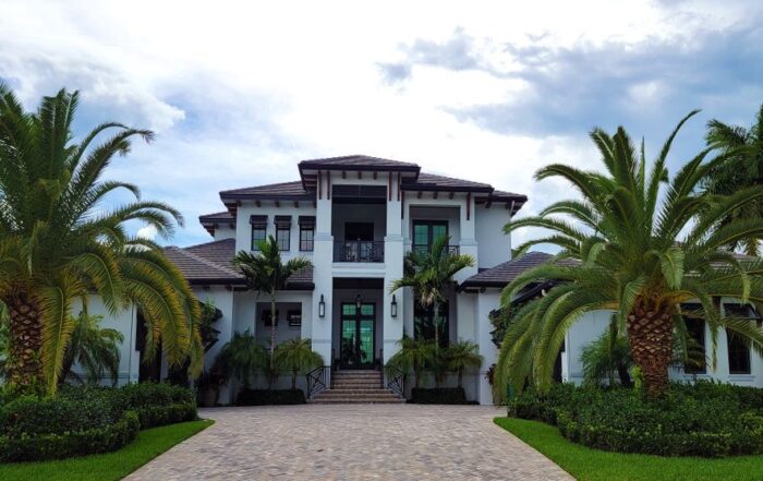 Stunning modern luxury beach house with large windows and a clean design, overlooking a bright blue ocean on a sunny day, ...