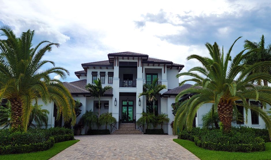 Stunning modern luxury beach house with large windows and a clean design, overlooking a bright blue ocean on a sunny day, ...